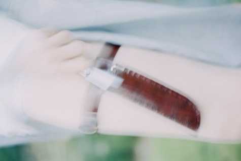 A blurred image of a knife in a sheath around a person's leg, there is a hand holding the knife's handle.