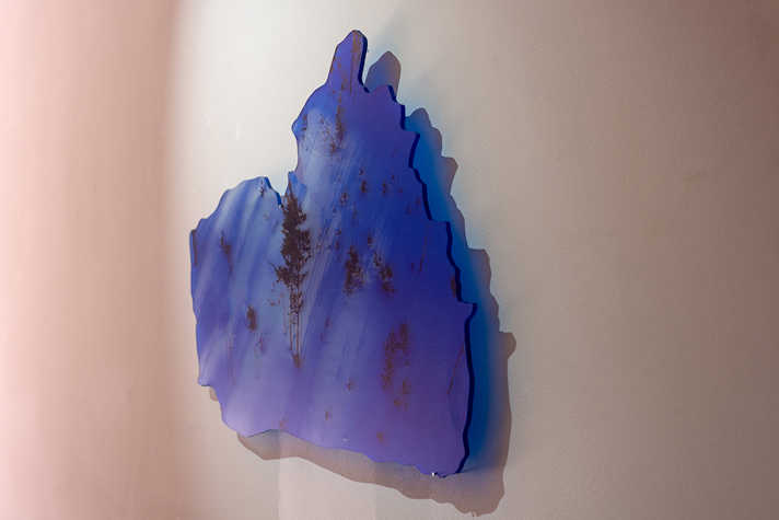 image from exhibition of object on wall of blue landscape of trees and snow