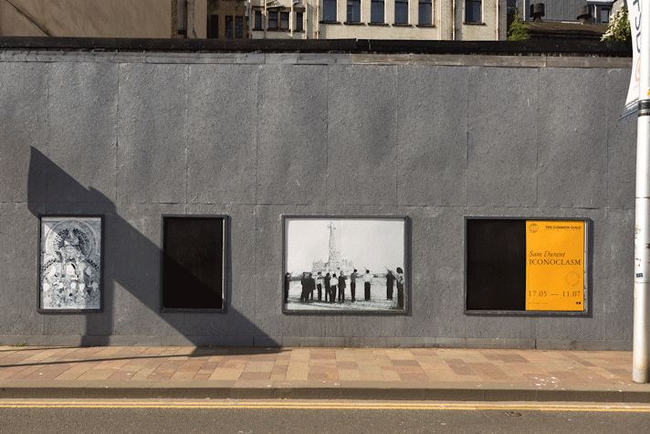 a series of public poster sites display intricate line drawings of statues being toppled