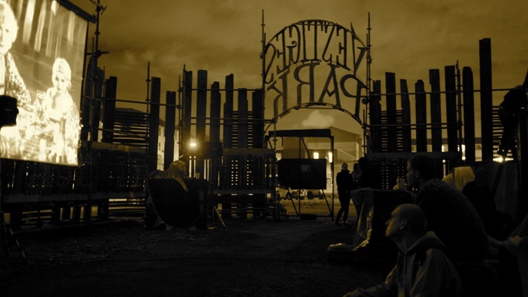 yellow filtered image of an outdoor scene with a fence reading 'vestiges park'