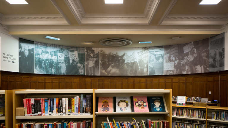 Interior of Glasgow Women's Library showing bookshelves in the foreground, and archive imagery (black and white photos) in the backgorund