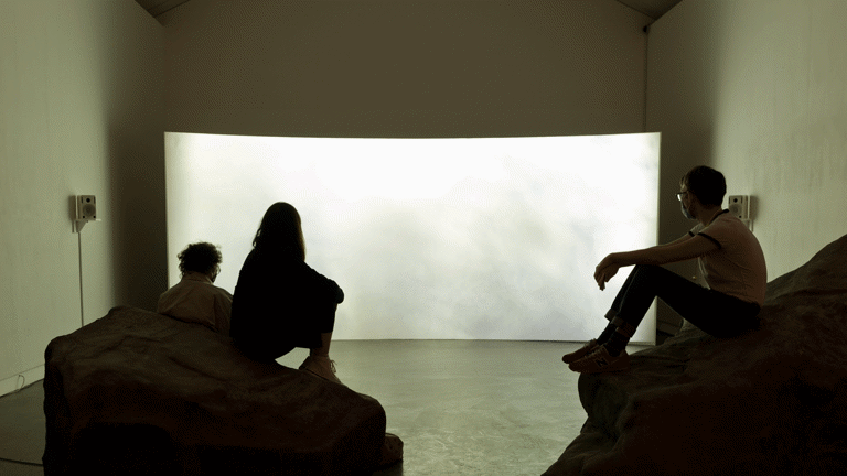 Installation view, people viewing film screen draped across the gallery space