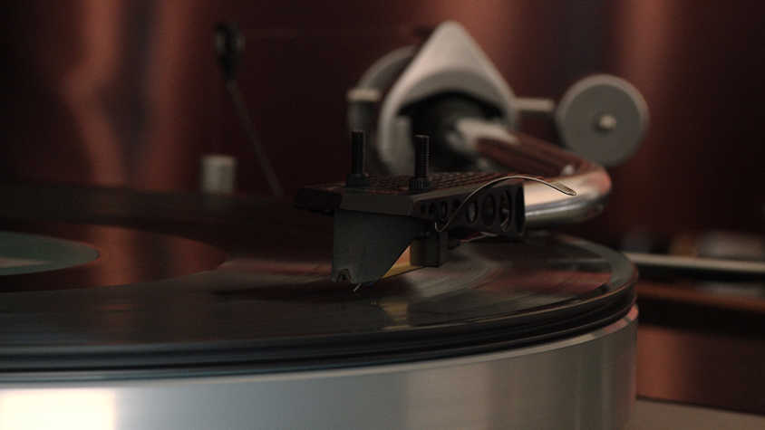 A close up of a needle of a record player, playing on top of a vinyl record.