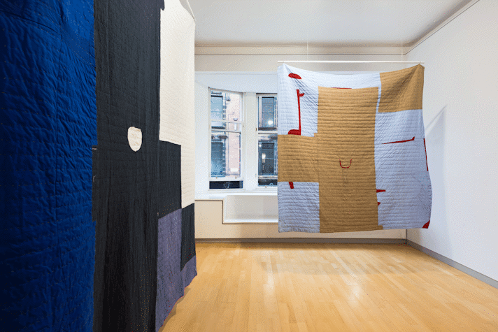 installation view image of large scale quilt hangings with abstract cut out shapes