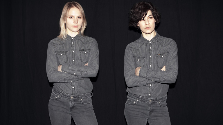 two women in the same outfit posing with their arms crossed