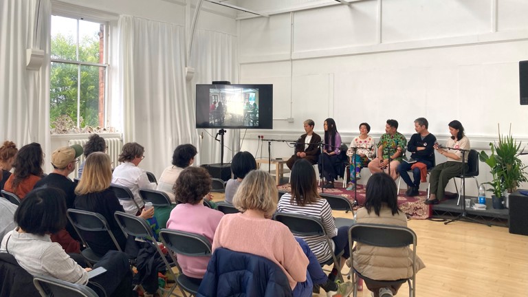 An image of people on a stage, speaking as a panel in front of an audience
