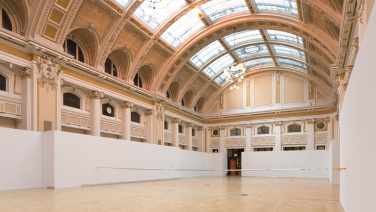 sculptural installation of chrome-coated pipe stretching across a large victorian hall