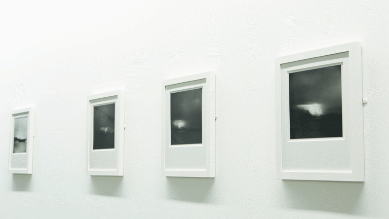 A series of white-framed black and white photographs on a white wall