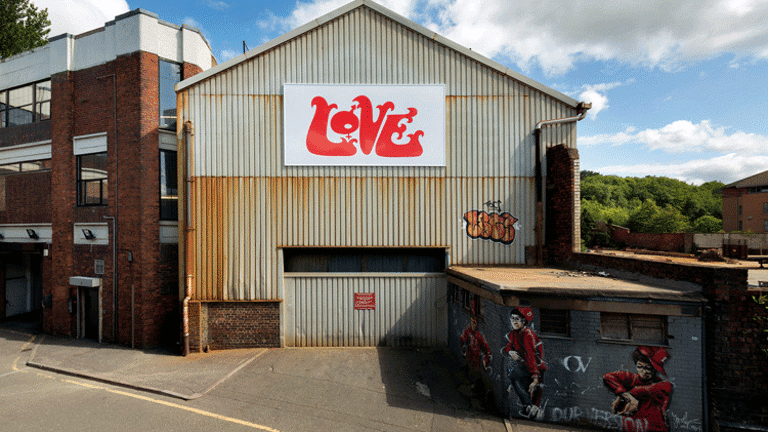 Photograph of an old warehouse with large sign reading 'Love' in graffiti lettering