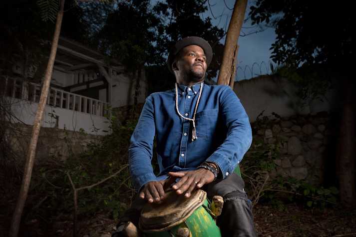 A man plays a drum and looks to the distance.