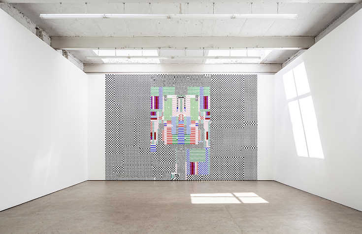 A large abstract artwork featuring squares of black and white, with coloured squares in the centre, is displayed on a wall in a light, airy space.