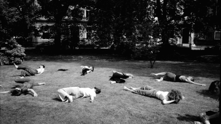 A black and white photograph of a park with a number of people lying on the grass