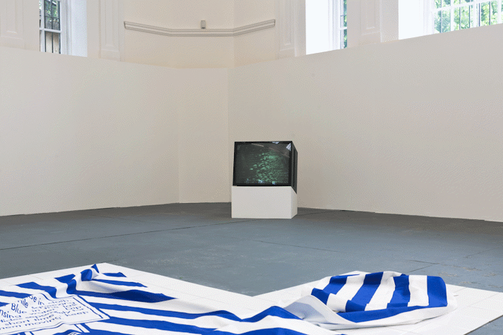an old square television set on a white plinth shows an abstract green pattern