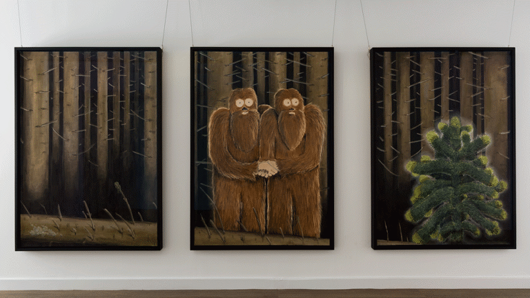 three large scale pastel drawings in black frames and portrait orientation hang on a white wall. they have a shared backdrop of a dark leafless forest. the left drawing shows tree trunks, the centre drawing shows two yeti figures embracing one another, the right drawing shows a monkeypuzzle tree. 