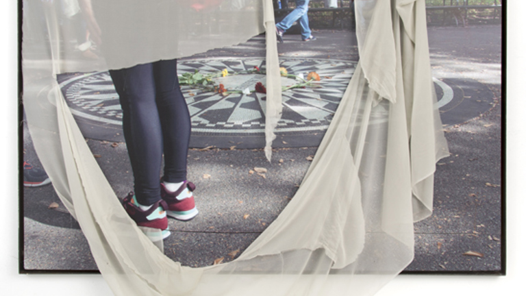 Photograph of a street with people, and a piece of cloth pinned and draped over the top