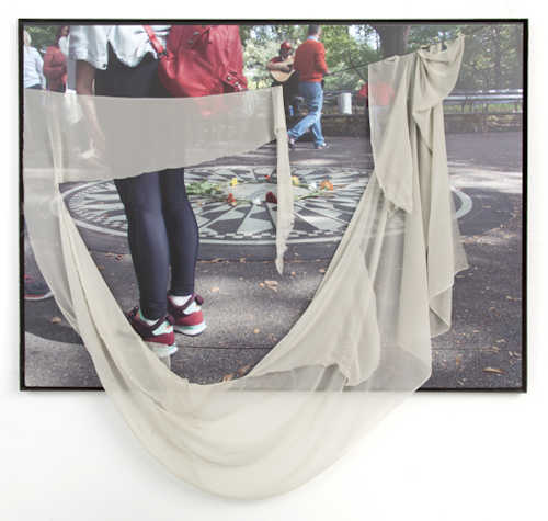 Photograph of a street with people, and a piece of cloth pinned and draped over the top