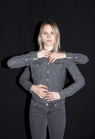 woman standing with her arms jutting outwards. a second pair of arms join hers from behind.