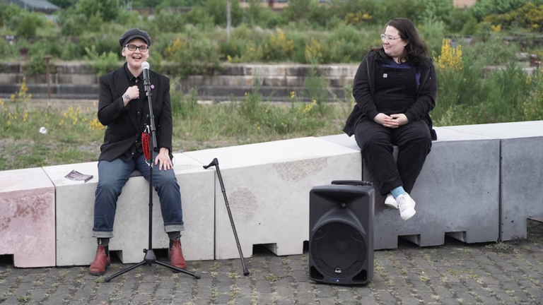 two people sitting on a wall, microphones in hand