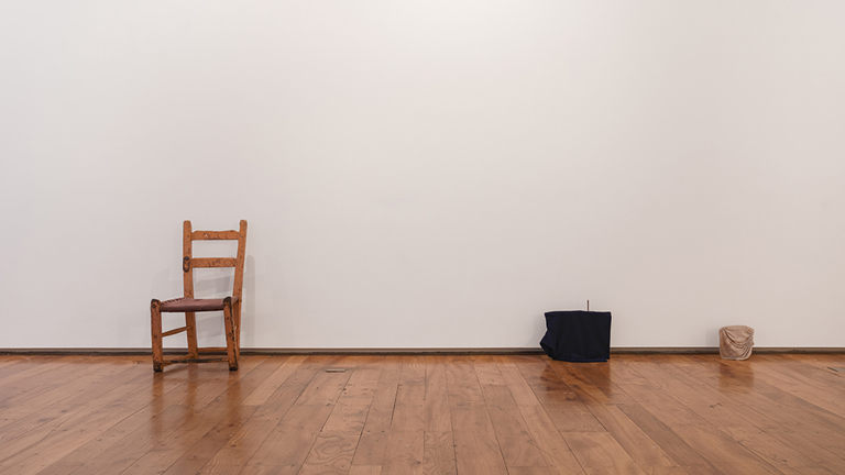 A chair is displayed against a white wall, alongside two other objects. 