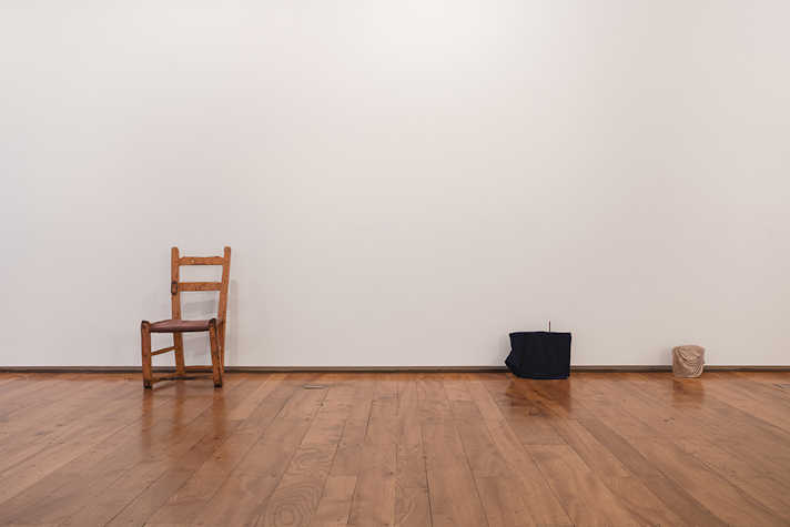 A chair is displayed against a white wall, alongside two other objects.