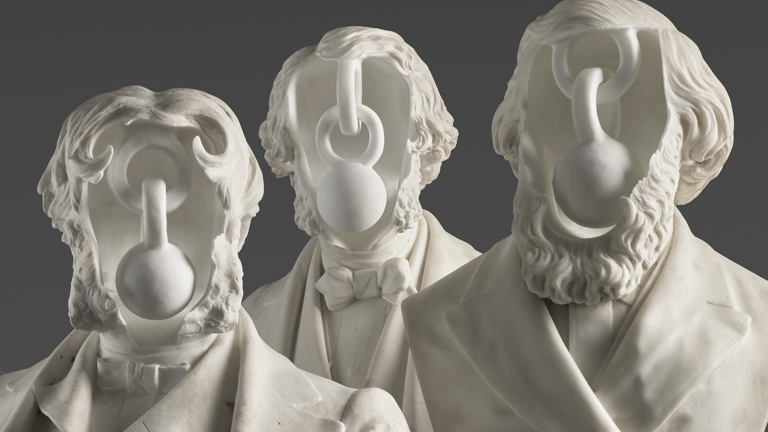 three white marble busts with hollowed faces. The busts have male features, with long facial hair, wearing suits.  Inside the hollow is chain links and weights. 
