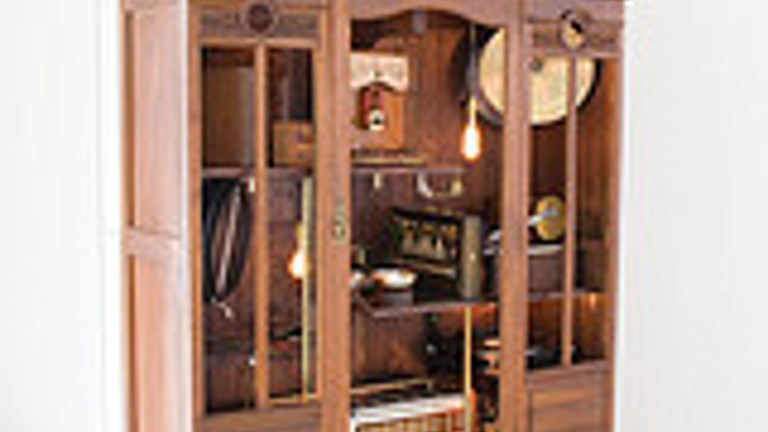 wooden cabinet with gramophone speakers attached to the top. inside are various instruments and items.