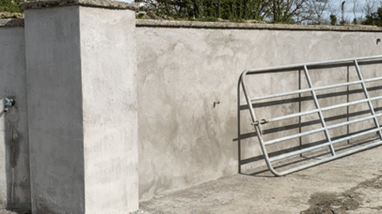 metal fence propped against a concrete wall with trees behind