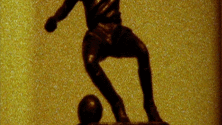 film still, half statue of a person in action about to kick a ball