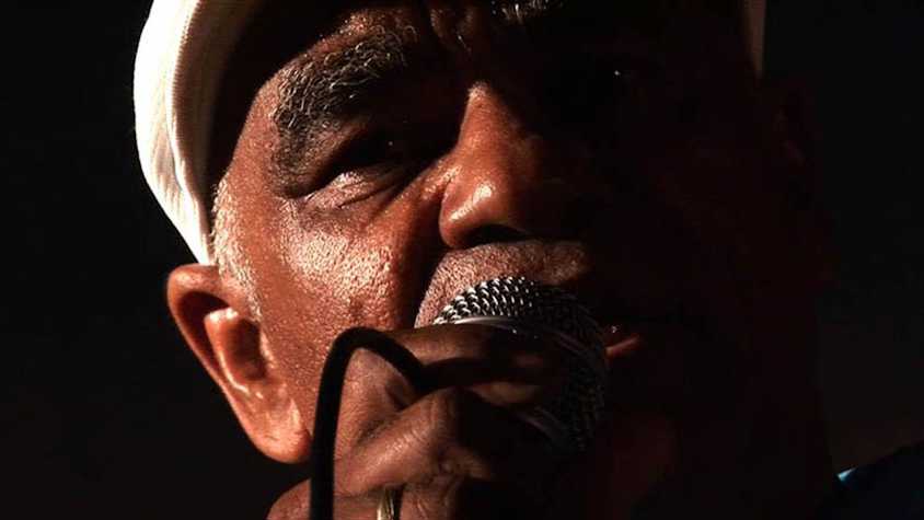dim and warmly lit close up of someone singing into a microphone