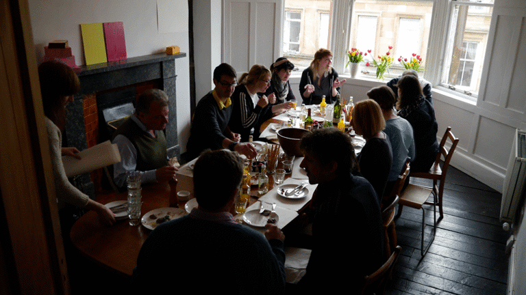 people around a dining table eating and talking