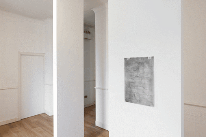 Installation view of a white-walled gallery with a work on paper visible