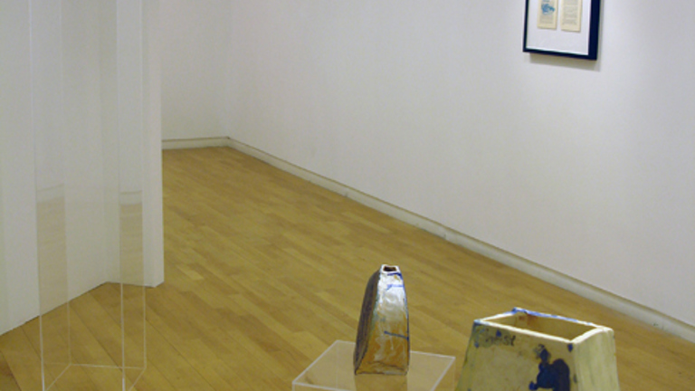 installation view of three ceramic pieces on perspex plinths of varying heights. in the background there is a framed print on the wall.