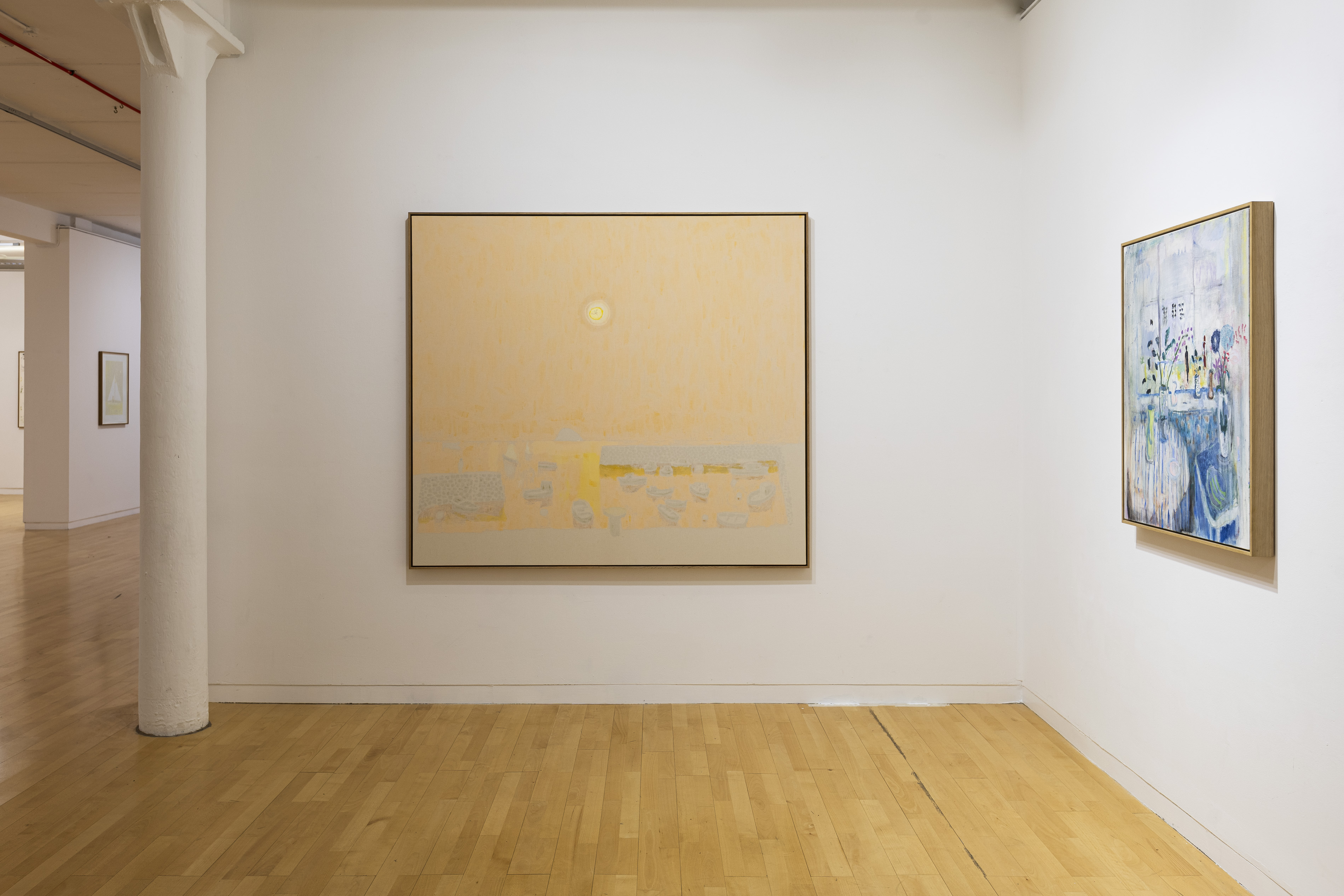 A gallery wall showing a pale yellow painting of a beach with small boats by Andrew Cranston or Lorna Robertson, beside a smaller painting of a blue and white still life on a table, visible through a doorway.
