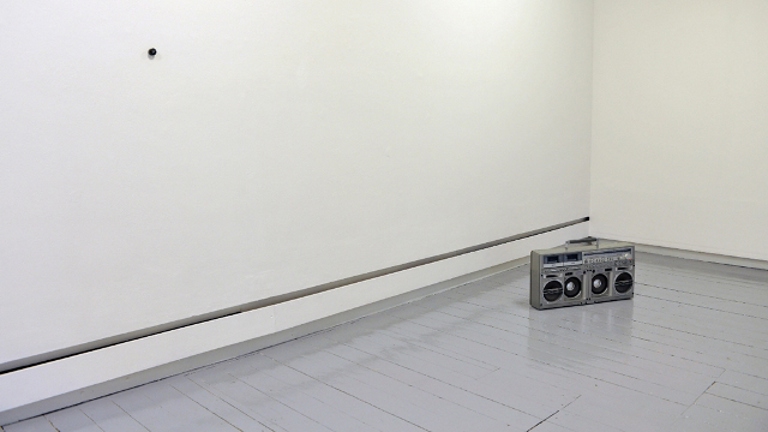 empty white room with a silver boombox on the floor 