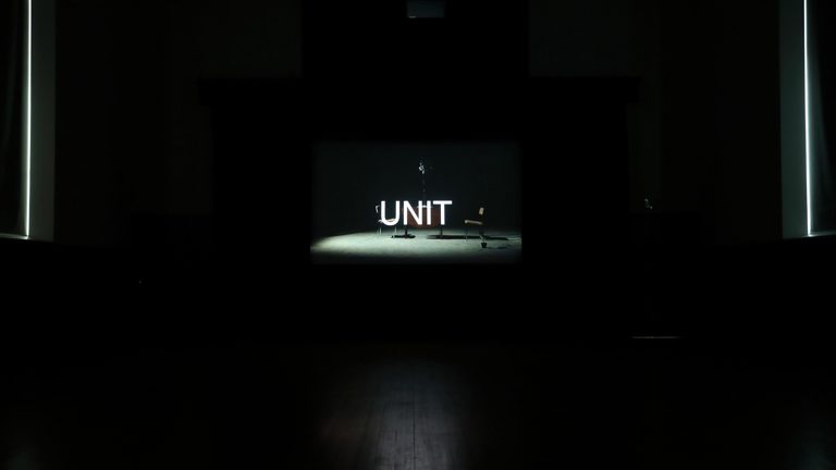Screen showing image of film with chairs and the word UNIT