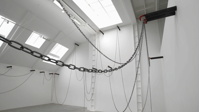 High ceilinged gallery space with a number of windows and a selection of chains drapped across the space