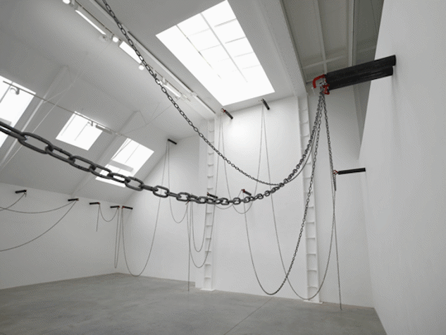 High ceilinged gallery space with a number of windows and a selection of chains drapped across the space