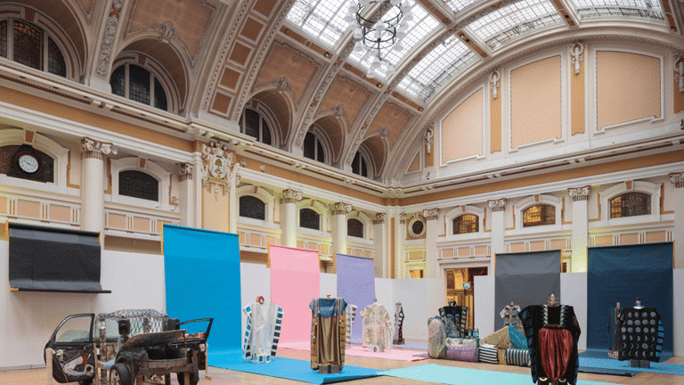 Installation view of exhibition in the Mitchell Library. Large vaulted ceiling with sculptural works below. 