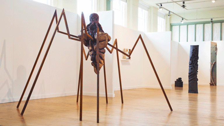 large sculptural installation with multiple long metal limbs and wooden centre. Other sculptural works visible in back ground