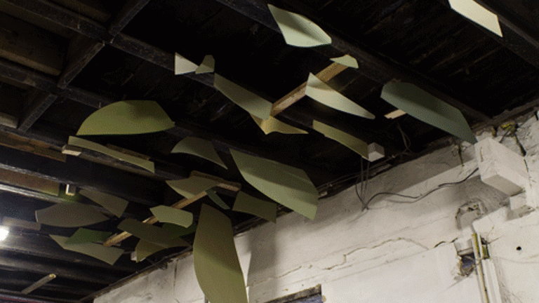 View of the ceiling of a gallery with sheets of shaped green material suspended 