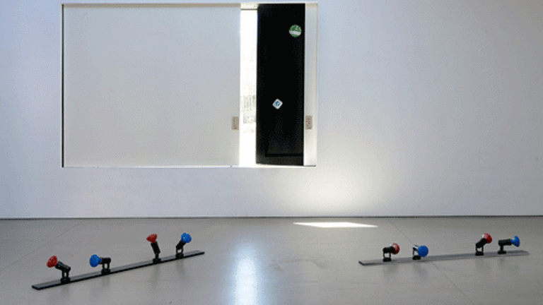 White-walled gallery with sculptural works including light fixings laid out on the floor