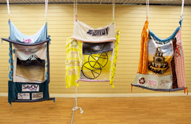 Suspended sculptural objects in what appears to be a former shop unit. The sculptures are made of plastic and fabric.