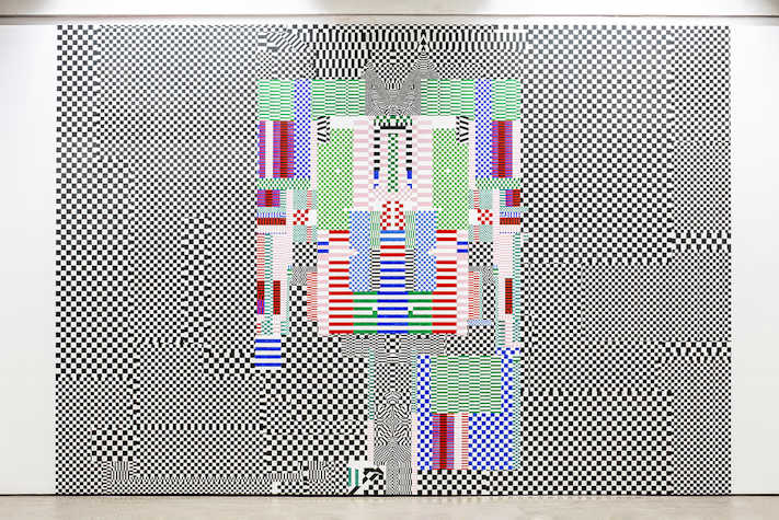 A large abstract artwork featuring squares of black and white, with coloured squares in the centre, is displayed on a wall.
