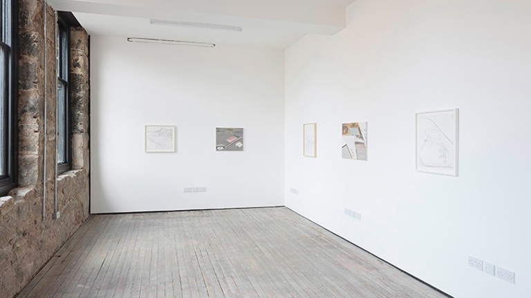 Installation view of exhibition in a white walled gallery with small works visible on the wall