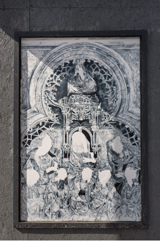 a billboard displays an intricate pencil drawing of a stone statue with the faces blanked out