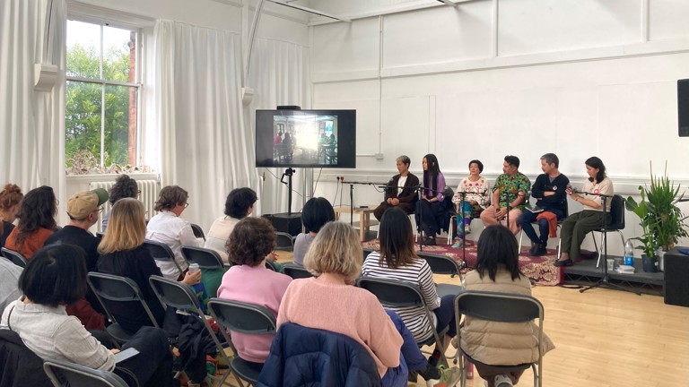 A panel discussion with six people speaking in front of a live audience 