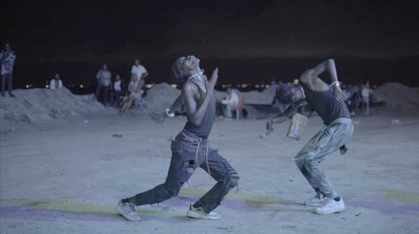 Two people dance in a desert at nighttime.
