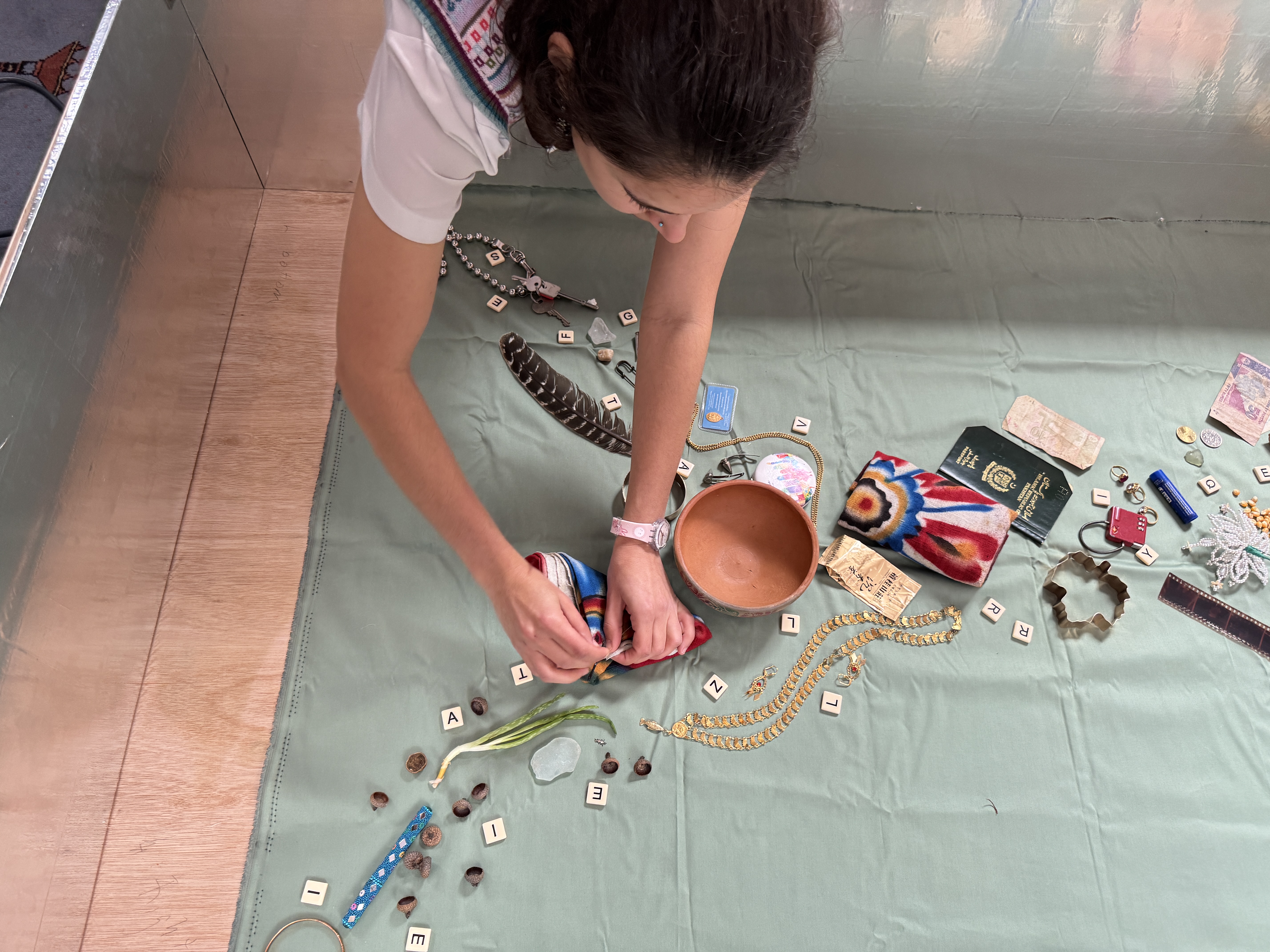 A photo of a woman doing a workshop, objects on the floor within a steel box.