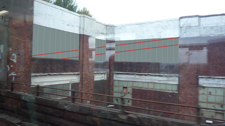 image from a train window of a building with two red lines across the windows