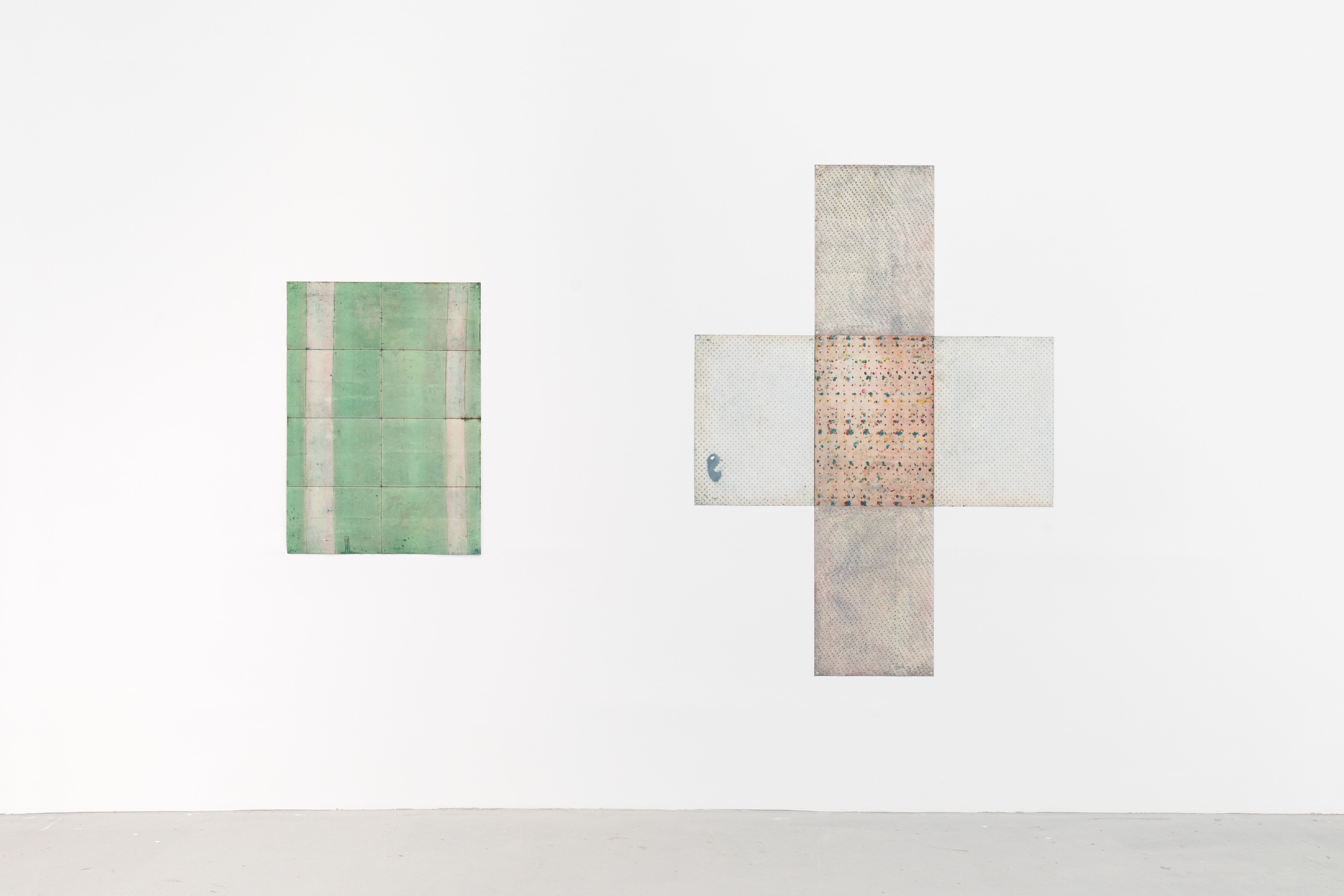 A work on paper. On the left is a green square, broken up by different textures. On the right is a cross shape, at its centre there is a peach textured piece on paper, extending from it is transparent blue squares. 